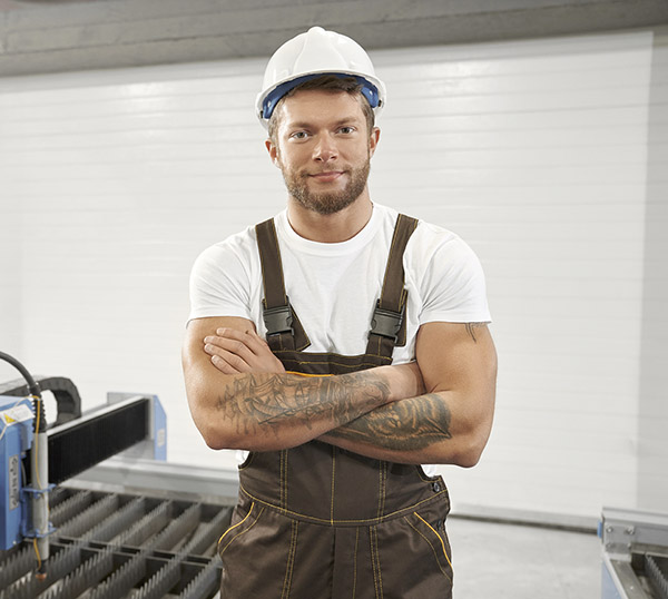 man in helmet standing with folded arms on factory